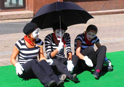 Участники фестивала пантомимы в Лондоне разыгрывают сцену под дождем