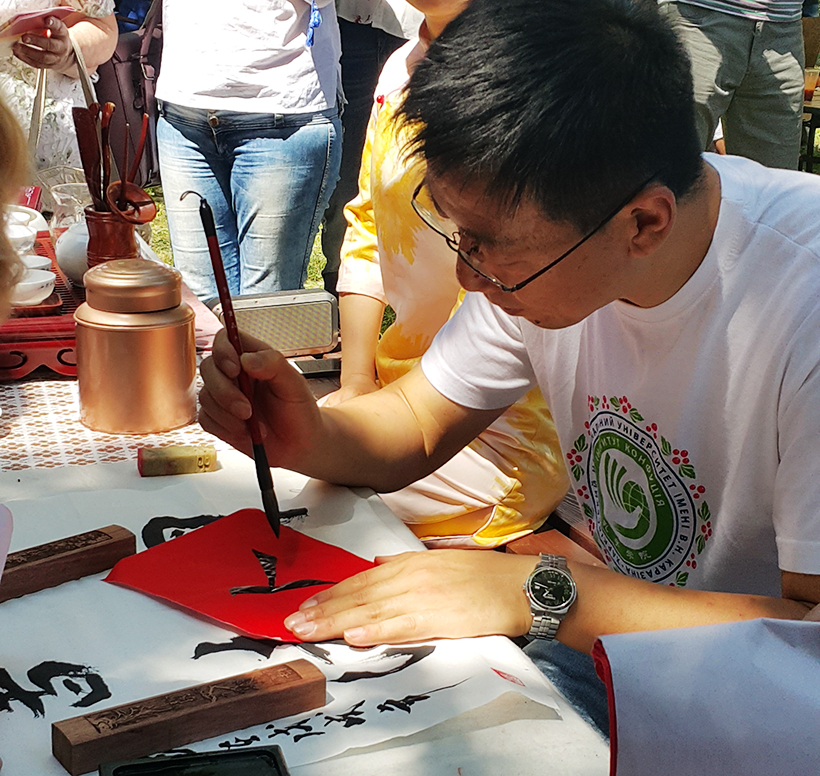 студенты из Китая пишут пожелания иероглифами на фестивале галушки